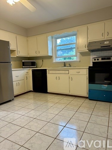 A kitchen with white cabinets and a tile floor.