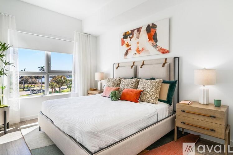 A bedroom with a large bed, a nightstand, and a painting on the wall.