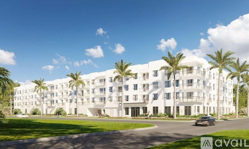 A modern white apartment building with palm trees in front.