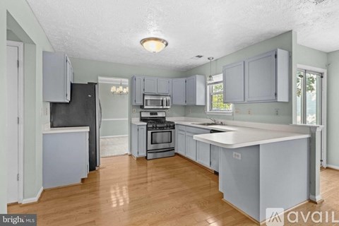 A kitchen with a black refrigerator and wooden floors.