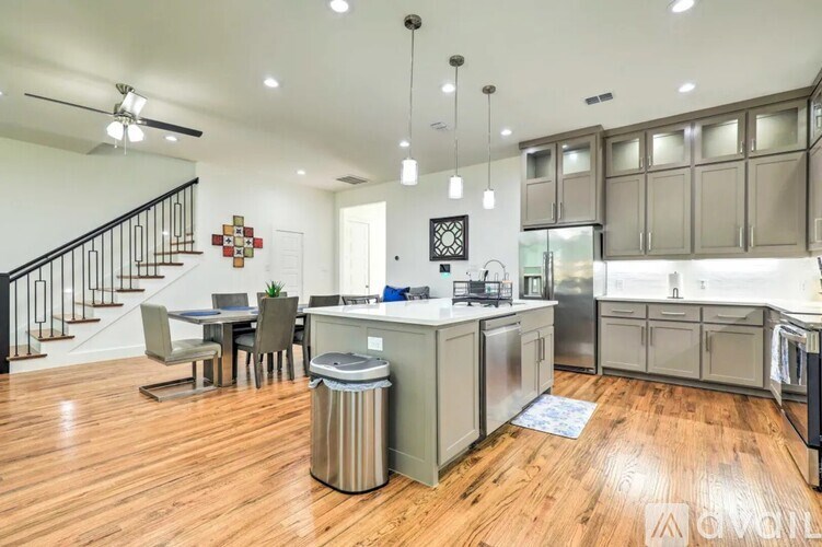 A modern kitchen with wooden floors and stainless steel appliances.