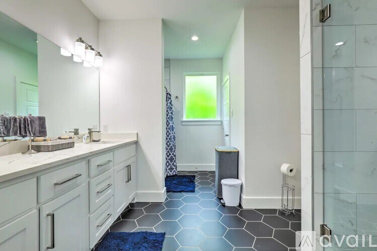 A bathroom with a blue rug on the floor.