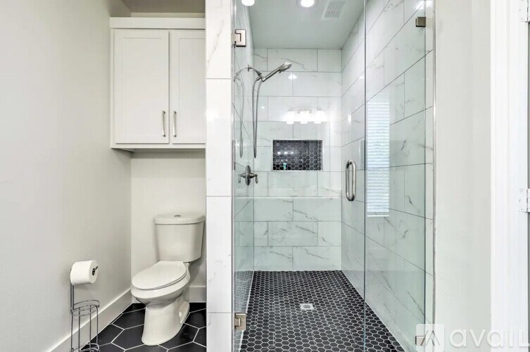 A white toilet sits in a bathroom with a glass shower stall.