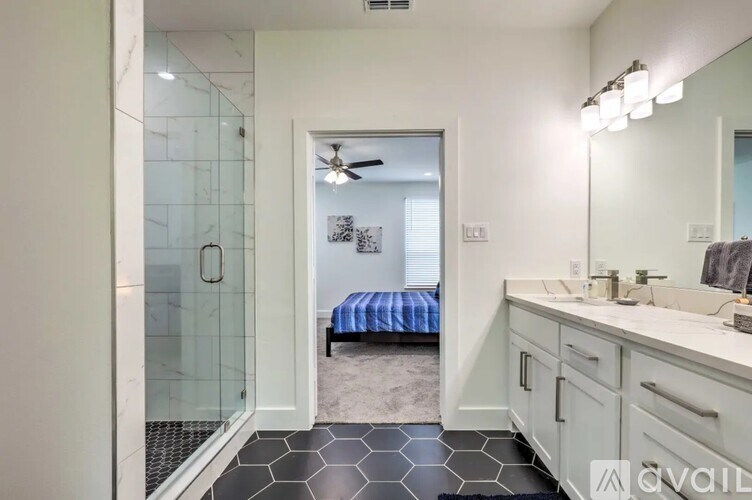 A bathroom with a walk-in shower, a bed, and a vanity.
