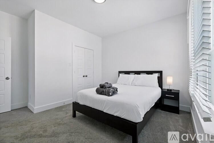 A bedroom with a bed, nightstand, and window with blinds.