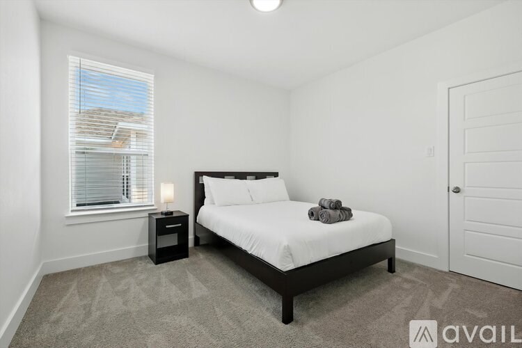 A bedroom with a bed, nightstand, and window.