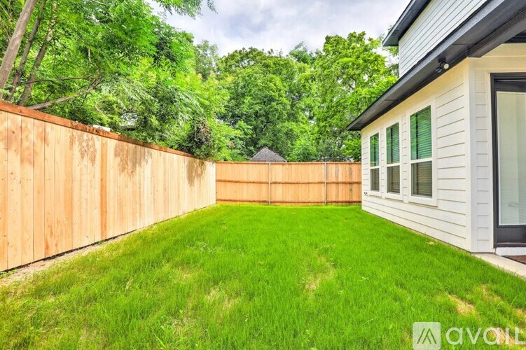 A backyard with a wooden fence and a house.
