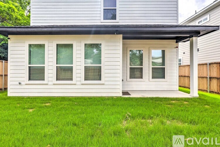 A house with a grey roof and white siding with a green lawn in front.