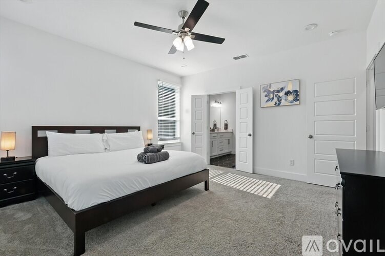 A bedroom with a large bed and a ceiling fan.