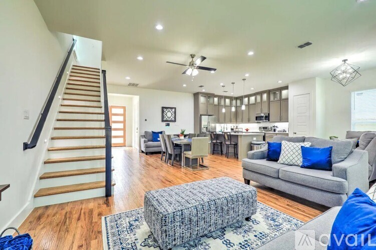 A living room with a grey couch and a wooden staircase.