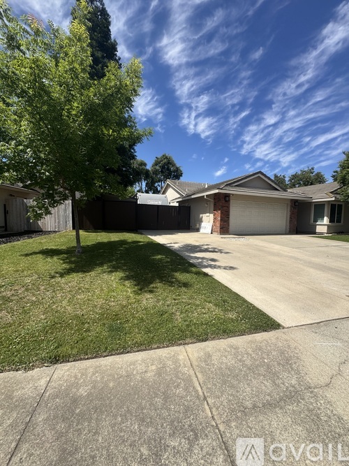 A house with a driveway and a tree in front.