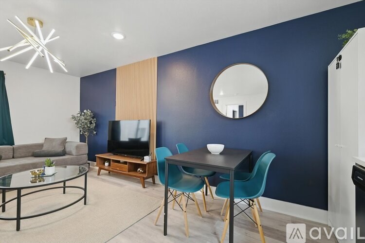 A living room with a blue wall and a round mirror.