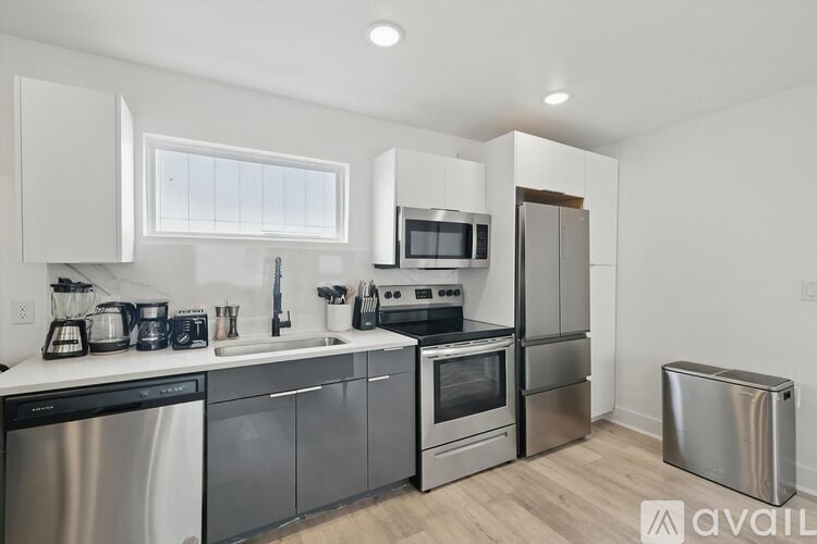 A modern kitchen with stainless steel appliances and wooden flooring.