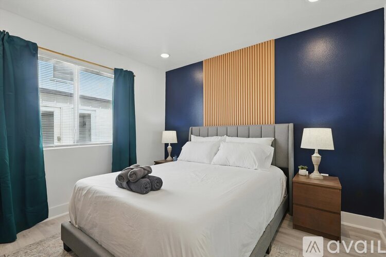 A bedroom with a large bed, a window with curtains, and two lamps on the nightstand.