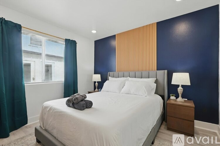A bedroom with a large bed, a window with curtains, and two lamps on the nightstand.