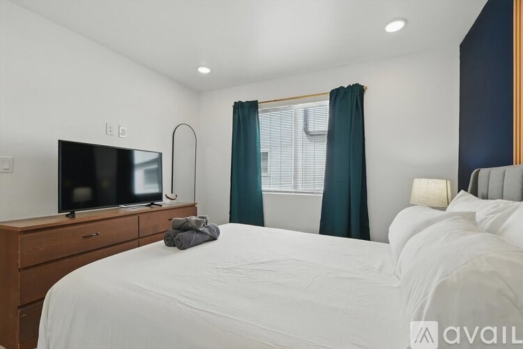 A bedroom with a large bed, a television, and a window with green curtains.