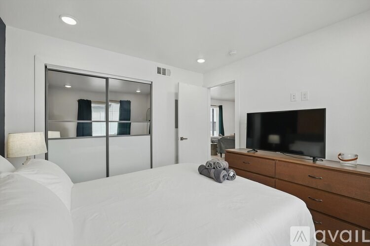 A bedroom with a bed, a dresser, and a television.