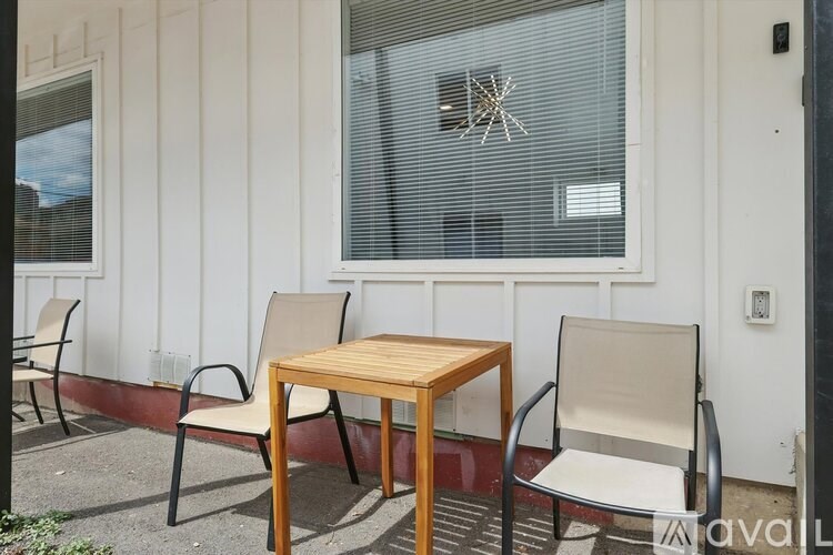 A wooden table and two chairs are placed outside a building.
