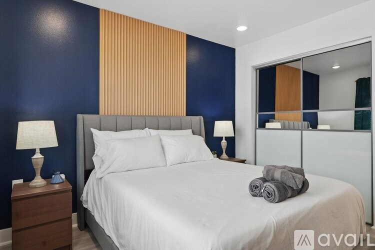 A bedroom with a bed, two lamps, and a nightstand.