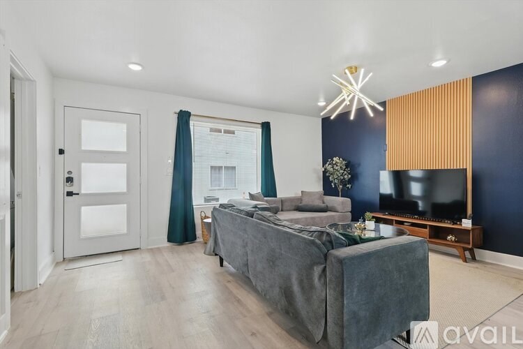 A modern bedroom with a grey bed and a grey sofa.