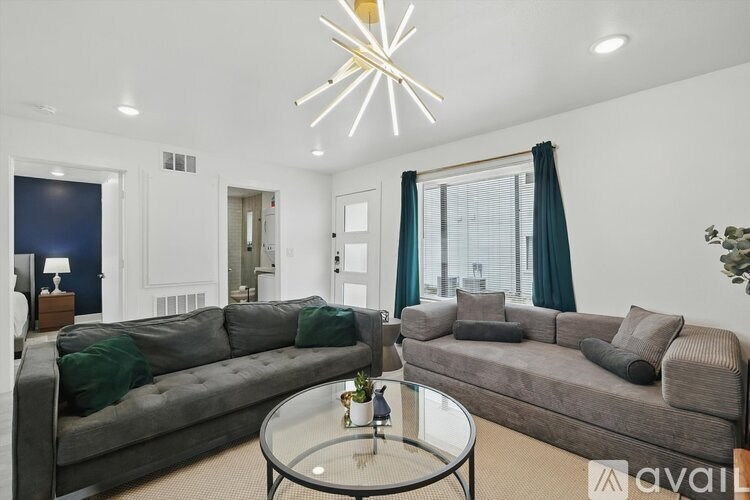 A modern living room with a grey sofa and a glass coffee table.