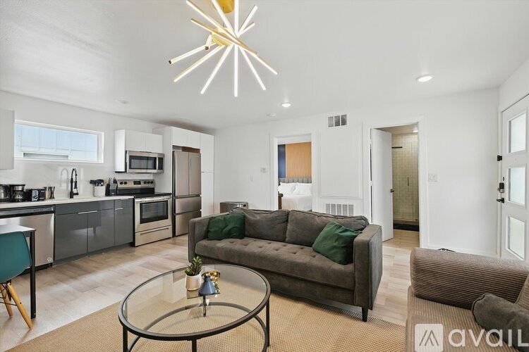A modern living room with a grey couch and a glass coffee table.