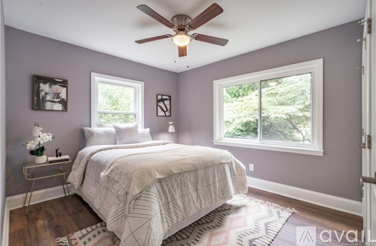 A bedroom with a bed, a ceiling fan, and a window.