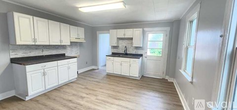 A kitchen with white cabinets and a black countertop.