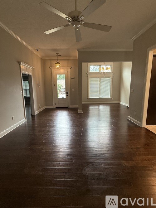 A room with a ceiling fan and wooden flooring.
