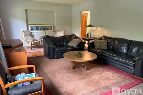 A living room with a black leather couch and a wooden coffee table.