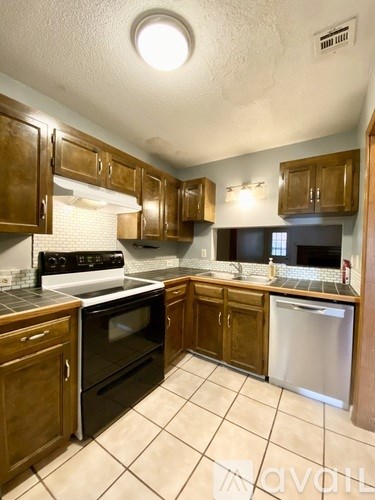 A kitchen with wooden cabinets and a stove top oven.