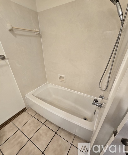 A white bathtub with a shower head and a white door.