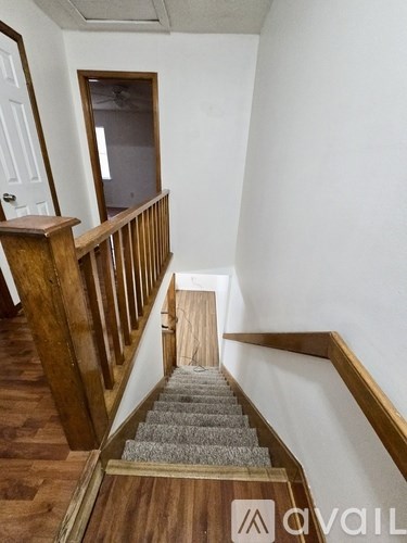 A staircase with wooden railings and a carpeted runner leads up to a landing with a door and a window.