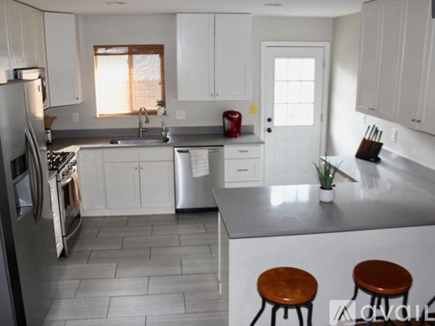 A kitchen with white cabinets and a grey countertop.