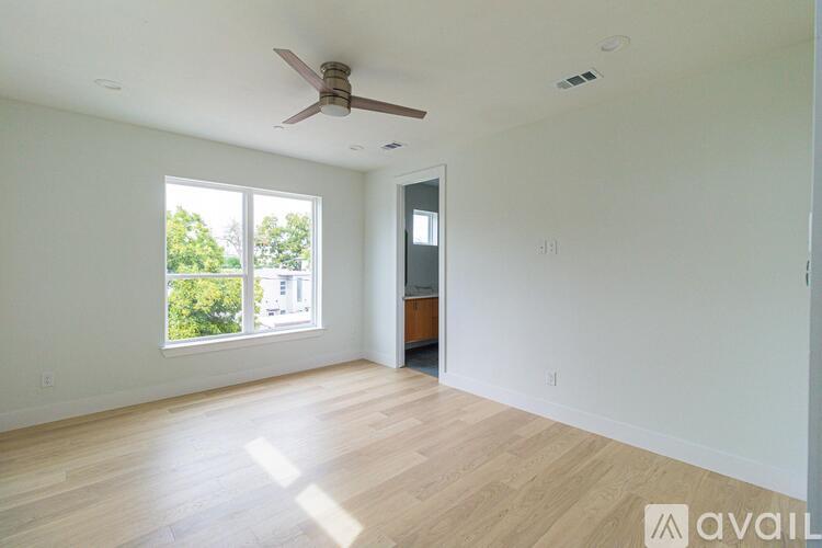 A spacious room with a ceiling fan and wooden flooring.