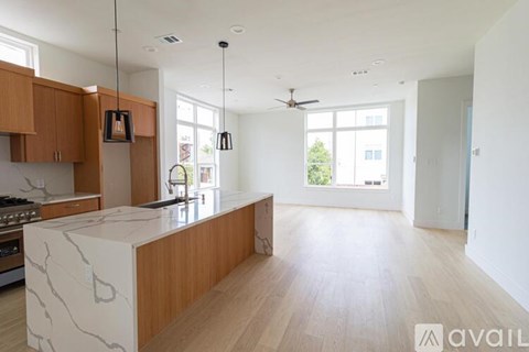 A modern kitchen with wooden cabinets and a marble island.