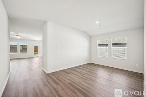 A spacious room with wooden flooring and white walls.