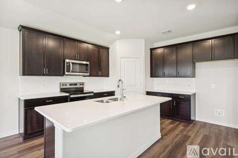 A kitchen with a white island and dark brown cabinets.