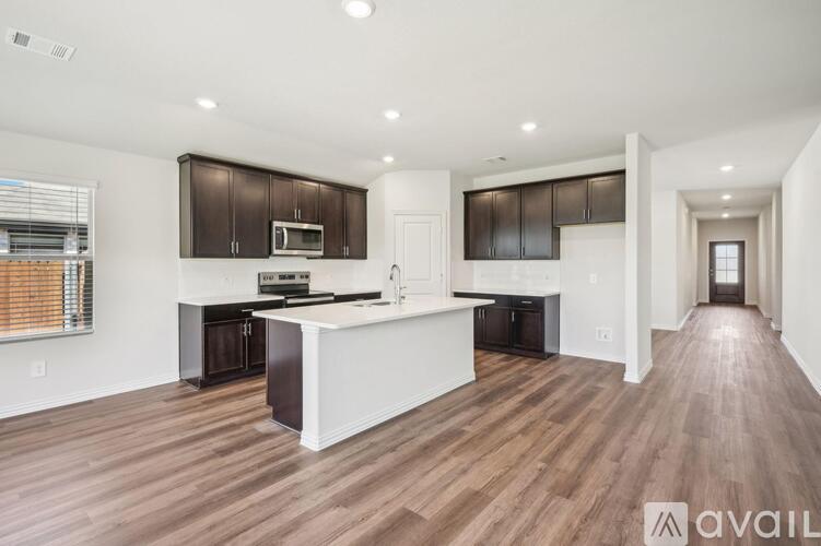 A spacious kitchen with dark brown cabinets and a white island.