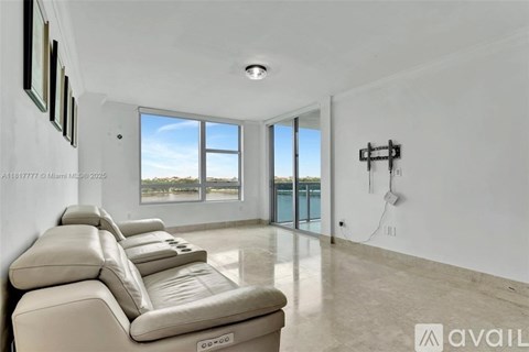 A living room with a row of beige leather sofas and a large window overlooking a body of water.
