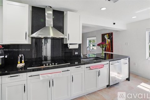 A kitchen with white cabinets and black countertops.