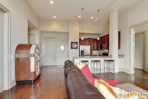 A brown leather couch sits in a living room with a wooden cabinet and a white fridge in the background.