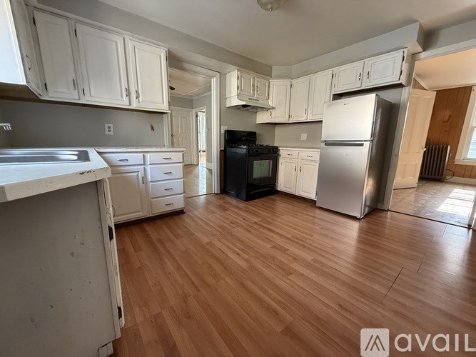 A kitchen with wooden floors and white cabinets.