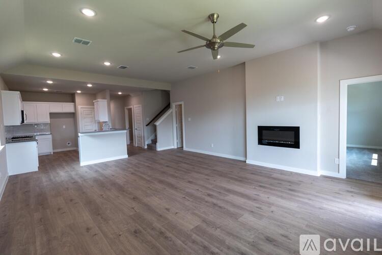 A spacious living room with a fireplace and a ceiling fan.