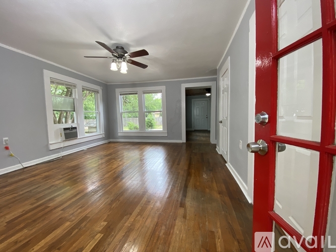 A room with a red door and wooden flooring.