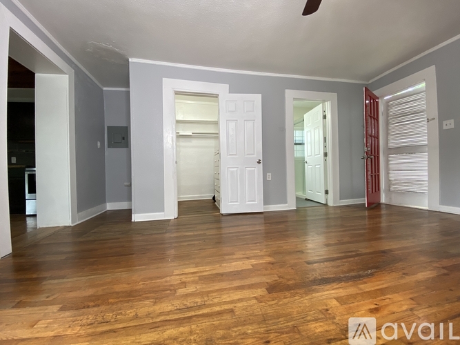 A room with wooden floors and white walls, with a door in the center.