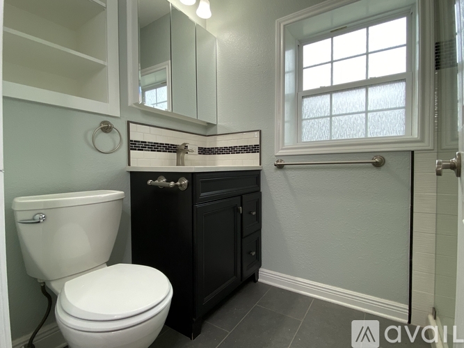 A bathroom with a toilet, sink, and a window.