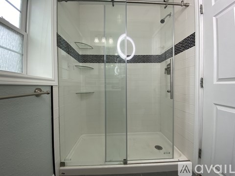 A modern bathroom with a glass shower enclosure and white tiled walls.