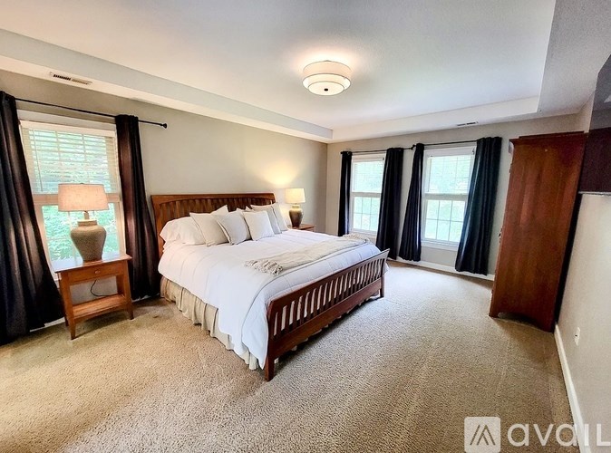 A well-lit bedroom with a large bed and a carpeted floor.