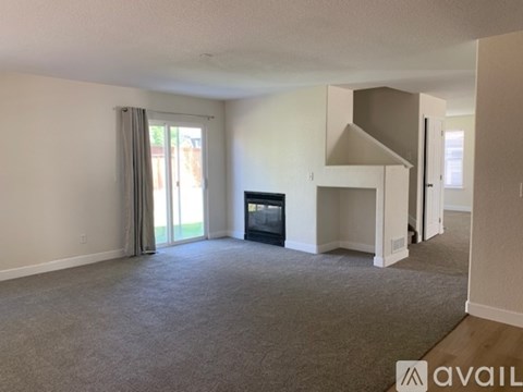 A living room with a grey carpet and a television.